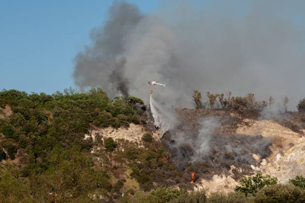 Wildfire erupts near Campi Flegrei volcanic area in Italy POZZUOLI, ITALY - JULY 13: An helicopter drops water over a wildfire in the Solfatara volcanic crater in the Campi Flegrei (Phlegraean Fields) volcanic region in Pozzuoli on July 13, 2026. The fire broke out in the undergrowth and quickly spread in the Pisciarelli area to several car dealerships, causing fuel tanks and tyres to explode. Eliano Imperato Anadolu Pozzuoli Italy. Editorial use only. Please get in touch for any other usage.  Copyright: x2026xAnadoluxElianoxImperatox