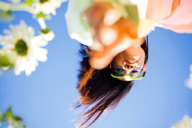 Eine junge Frau mit Sonnenbrille streckt die Hand in Richtung Kamera aus; sie ist von weißen Blumen umgeben, vor einem strahlend blauen Himmel in einer farbenfrohen Landschaft im Freien. Young woman in sunglasses extends her hand towards the camera, framed by white flowers and a bright blue sky in a sunny outdoor environment (License=RF) ,model released, Symbolfoto Copyright: xZoonar.com DashaxPetrenkox 25331342 ,model released, Symbolfoto ,property released