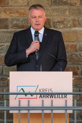 Ausstellungseroeffnung von We AHR strong. Fuenf Jahre, ein neuer Blick in Altenahr (Foto vom 14.07.2026: Ministerpräsident von Rheinland-Pfalz, Gordon Schnieder, spricht). Ueber 60 Portraets und dazu persoenliche Geschichten: Die Freiluftausstellung We AHR strong. Fuenf Jahre, ein neuer Blick rueckt fuenf Jahre nach der Flutkatastrophe die Menschen im Ahrtal in den Fokus. Die Praesentation soll zurueckblicken und nach vorne schauen. Bis zum 24. August sind entlang der Ahr in Altenahr, Bad Neuenahr-Ahrweiler, Sinzig und Schuld die Portraets des Fotografen Ruben Timman vom Museum of Humanity zu sehen. (Siehe epd-Bericht vom 14.07.2026) EDITORIAL USE ONLY *** Exhibition opening for We AHR strong: Five Years, a new perspective on Alten Copyright: epd-bild GuidoxSchiefer 20260714-DSCF8092