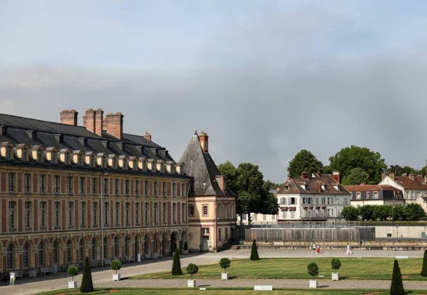 (260714) -- SEINE-ET-MARNE, July 14, 2026 -- Tourists visit the Palace of Fontainebleau in Seine-et-Marne, France, as smoke from a wildfire is seen in the distance, on July 14, 2026. French police have detained 59 people across the country in connection with wildfires, including two suspects linked to the blaze in the Fontainebleau forest in Seine-et-Marne department, southeast of Paris, French Interior Minister Laurent Nunez said on Monday. The wildfire in the Fontainebleau forest broke out on Sunday evening and continued to spread on Monday. ) FRANCE-SEINE-ET-MARNE-FONTAINEBLEAU-WILDFIRE WuxHuiwo 