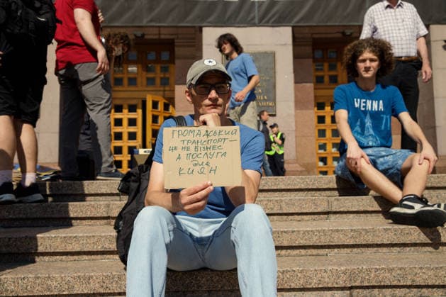 A man holds a placard reading Public Transport Is Not Business, but a Service for Kyivans during the Preserve Affordable Transport in Kyiv rally against the increase in municipal transport fares outside the Kyiv City State Administration building, Kyiv, Ukraine, July 14, 2026. The capital plans to raise the fare for municipal transport to UAH 30 per single trip. The new tariffs will take effect from July 15, 2026. (Photo by Marianna Kotyk Ukrinform) Kyivans protest against municipal transport fare hike  Copyright: xMariannaxKotykx