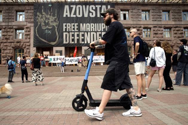 A man pushes an electric kick scooter past activists protesting against the increase in municipal transport fares during the Preserve Affordable Transport in Kyiv rally outside the Kyiv City State Administration building, Kyiv, Ukraine, July 14, 2026. The capital plans to raise the fare for municipal transport to UAH 30 per single trip. The new tariffs will take effect from July 15, 2026. (Photo by Marianna Kotyk Ukrinform) Kyivans protest against municipal transport fare hike  Copyright: xMariannaxKotykx