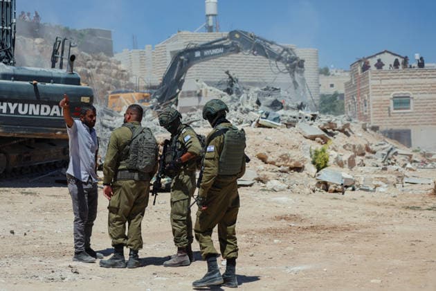 Hebron West Bank Home Demolition Israeli forces stand near an excavator as a Palestinian home is demolished in Al-Deirat, south of Hebron, occupied West Bank on July 14, 2026. Israeli forces demolish the home of Osama Masaaf on the grounds that it lacked an Israeli-issued building permit, displacing a Palestinian family of eight. Hebron West Bank Palestinian Territories Copyright: xMosabxShawerx