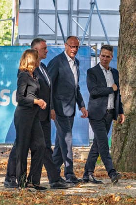 Besuch im Kurpark Bad Neuenahr-Ahrweiler - Fünf Jahre Ahrtalflut Stellvertretende Ministerpräsidentin Rheinland-Pfalz Sabine BÄTZING-LICHTENTHÄLER (SPD), Ministerpräsident Rheinland-Pfalz Gordon SCHNIEDER (CDU), Bundeskanzler Friedrich MERZ (CDU) und Bürgermeister der Stadt Bad Neuenahr-Ahrweiler Pascal ROWALD (CDU) im Gespräch mit Ehrenamtlichen und Gewerbetreibenden im Kurpark Bad Neuenahr-Ahrweiler. Beim Besuch zum fünften Jahrestag der Flutkatastrophe im Ahrtal informierten sie sich über den Stand des Wiederaufbaus. Bad Neuenahr-Ahrweiler Rheinland-Pfalz Deutschland *** Visit to the Bad Neuenahr-Ahrweiler Spa Park: Five Years Since the Ahr Valley Floods. Sabine BÄTZING LICHTENTHÄLER (SPD), Deputy Minister-President of Rhinelan Copyright: xMarcxJohnx