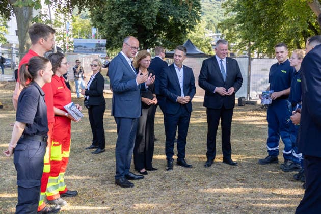Besuch im Kurpark Bad Neuenahr-Ahrweiler - Fünf Jahre Ahrtalflut Bundeskanzler Friedrich MERZ, Stellvertretende Ministerpräsidentin Rheinland-Pfalz Sabine BÄTZING-LICHTENTHÄLER (SPD), Bürgermeister der Stadt Bad Neuenahr-Ahrweiler Pascal ROWALD (CDU) und Ministerpräsident Gordon SCHNIEDER im Gespräch mit Ehrenamtlichen und Gewerbetreibenden im Kurpark Bad Neuenahr-Ahrweiler. Beim Besuch zum fünften Jahrestag der Flutkatastrophe im Ahrtal informierten sie sich über den Stand des Wiederaufbaus. Bad Neuenahr-Ahrweiler Rheinland-Pfalz Deutschland *** Visit to the Bad Neuenahr Ahrweiler Spa Park: Five Years Since the Ahr Valley Floods. Federal Chancellor Friedrich MERZ; Sabine BÄTZING LICHTENTHÄLER, SPD, Deputy Minister-President of Rh Copyright: xMarcxJohnx