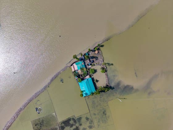 Aftermath Of Floodwaters In Chattogram A top-down aerial perspective shows a single homestead completely encircled by receding yet deep floodwaters in Banshkhali, Chattogram, Bangladesh, on July 14, 2026. Flood waters in Banshkhali and Satkania in Chittagong are slowly receding, with many areas still knee-deep in water. As the water recedes, collapsed mud houses, damaged structures, destroyed brick kilns and severely damaged agricultural land are becoming visible, displacing thousands of people. Chattogram Bangladesh  Copyright: xZakirxHossainx originalFilename: hossain-notitle260714_np0VS.jpg