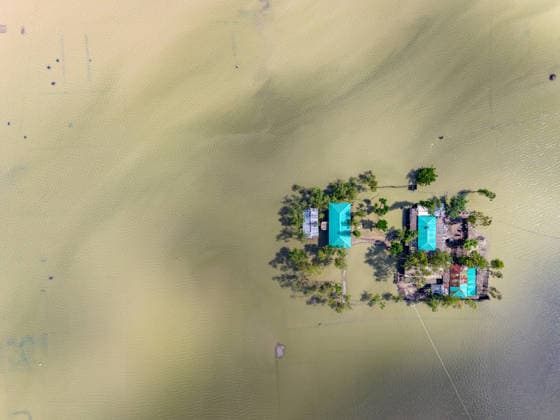Aftermath Of Floodwaters In Chattogram A vertical top-down drone perspective captures a residential compound isolated by deep, receding floodwaters following heavy rains in Banshkhali, Chattogram, Bangladesh, on July 14, 2026. Flood waters in Banshkhali and Satkania in Chittagong are slowly receding, with many areas still knee-deep in water. As the water recedes, collapsed mud houses, damaged structures, destroyed brick kilns and severely damaged agricultural land are becoming visible, displacing thousands of people. Chattogram Bangladesh  Copyright: xZakirxHossainx originalFilename: hossain-notitle260714_npZkf.jpg