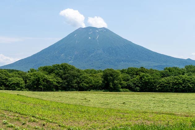 Der Vulkan Mount Yotei (Yoteizan) erhebt sich über der Landschaft in Hokkaido, Japan. Der nahezu symmetrische Stratovulkan mit verbliebenen Schneefeldern zählt zu den markantesten Naturdenkmälern der Region Niseko und ist ein beliebtes Ziel für Wanderer und Naturtouristen
