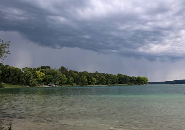 Ein Sommertag bei Feldafing (Landkreis Starnberg). Hier der Blick auf den Starnberger See an der Roseninsel auf dunklen Himmel, Unwetter im Anmarsch, Unwetteralarm, Starkregen, Wetterfoto, Wetterbild, Gewitter,dunkle Wolken, Gefahr, Unwettergefahr, Hagel , Regenfäden, ausregnen, Regenschauer *** A summer day near Feldafing in the Starnberg district. Here is a view of Lake Starnberg near Roseninsel against a dark sky, with a storm approaching, a severe weather warning, heavy rain, weather photo, weather image, thunderstorm, dark clouds, danger, risk of severe weather, hail, raindrops, pouring rain, rain shower