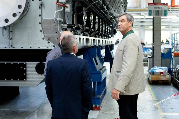 Augsburg, Bavaria, Germany - July 17, 2026: Company visit to Everllence SE at its Augsburg facility. Everllence (formerly MAN Energy Solutions) develops, among other things, large engines, large heat pumps, and technologies for hydrogen and ammonia applications. Dr. Markus Söder (Minister-President of Bavaria, CSU) and Dr. Uwe Lauber (Chairman of the Executive Board of Everllence (formerly MAN Energy Solutions SE, previously MAN Diesel & Turbo SE), CEO) in the production hall next to a large diesel engine intended for use in the shipping industry *** Unternehmensbesuch bei Everllence SE am Unternehmensstandort in Augsburg. Everllence (ehemals MAN Energy Solutions) entwickelt unter anderem Großmotoren, Großwärmepumpen sowie Technologien