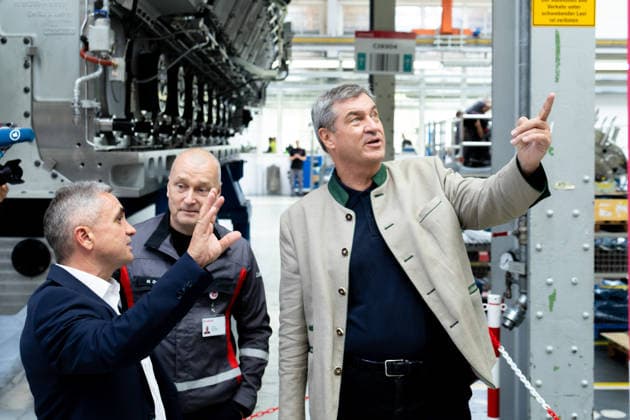 Augsburg, Bavaria, Germany - July 17, 2026: Company visit to Everllence SE at its Augsburg facility. Everllence (formerly MAN Energy Solutions) develops, among other things, large engines, large heat pumps, and technologies for hydrogen and ammonia applications. Dr. Markus Söder (Minister-President of Bavaria, CSU) and Dr. Uwe Lauber (Chairman of the Executive Board of Everllence (formerly MAN Energy Solutions SE, previously MAN Diesel & Turbo SE), CEO) in the production hall next to a large diesel engine intended for use in the shipping industry *** Unternehmensbesuch bei Everllence SE am Unternehmensstandort in Augsburg. Everllence (ehemals MAN Energy Solutions) entwickelt unter anderem Großmotoren, Großwärmepumpen sowie Technologien