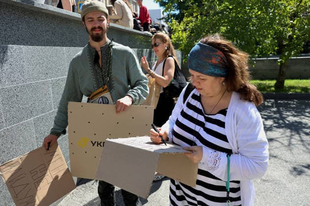 A woman writes a slogan on a piece of cardboard during a protest action against the dismissal of Ukrainian Defence Minister Mykhailo Fedorov in Svobody Square, Kharkiv, Ukraine, July 17, 2026. (Photo by Viacheslav Madiievskyi Ukrinform) Activists rally in support of Mykhailo Fedorov in Kharkiv  Copyright: xViacheslavxMadiievskyix