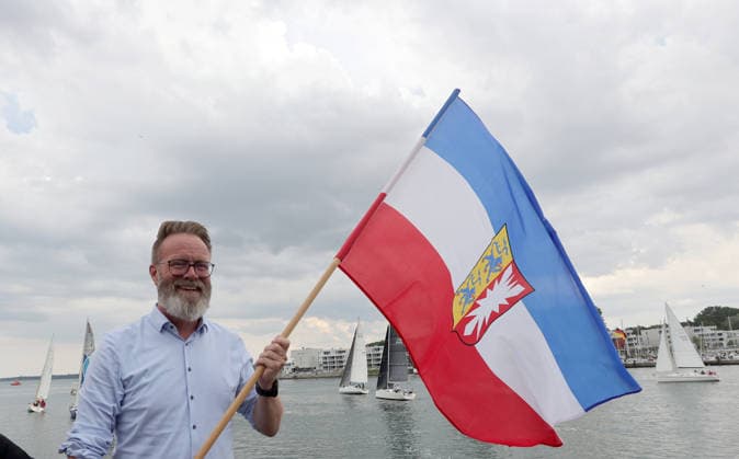 Wirtschaftsminister Schleswig Holstein, Claus Ruhe Madsen startet die erste Regatta der diesjaehrigen Travemuender Woche mit dem Schwenken der Landesfahne Impressionen der Eroeffung der 137.Travemuender Woche Reisen, Tourismus, urlaub, Ferien, Ostsee, Travemuende, Segelsport Travemuende *** Schleswig-Holstein Minister of Economic Affairs, Claus Ruhe Madsen kicks off the first regatta of this year’s Travemünde Week by raising the state flag. Highlights from the opening of the 137th Travemünde Week. Travel, tourism, vacation, holidays, Baltic Sea, Travemünde, sailing in Travemünde