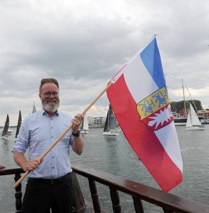 Wirtschaftsminister Schleswig Holstein, Claus Ruhe Madsen startet die erste Regatta der diesjaehrigen Travemuender Woche mit dem Schwenken der Landesfahne Impressionen der Eroeffung der 137.Travemuender Woche Reisen, Tourismus, urlaub, Ferien, Ostsee, Travemuende, Segelsport Travemuende *** Schleswig-Holstein Minister of Economic Affairs, Claus Ruhe Madsen kicks off the first regatta of this year’s Travemünde Week by raising the state flag. Highlights from the opening of the 137th Travemünde Week. Travel, tourism, vacation, holidays, Baltic Sea, Travemünde, sailing in Travemünde