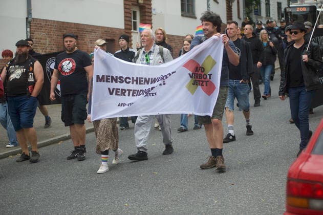 Flensburg, Schleswig-Holstein Demo Projekt M1llion öEinigkeit für Deutschland™. Hier: Gegendemonstranten aus der linken Szene marschieren auf der Friesischen Straße..Eine Person mit schwarzen T-Shirt und Aufschrift Good Night White Pride. Weiter halten Personen ein Transparent mit Aufschrift Menschenwürde verteidigen! AfD-Verbot jetzt. Aufnahme vom 18.07.2026, Flensburg. Aufnahme vom 18.07.2026, Flensburg. *** Flensburg, Schleswig-Holstein: M1llion Unity for Germany™ Demonstration Here, counter-demonstrators from the left-wing scene are marching on Friesische Straße. One person is wearing a black T-shirt with the words Good Night White Pride. Further along, people are holding a banner reading Defend Human Dignity—Ban the AfD No