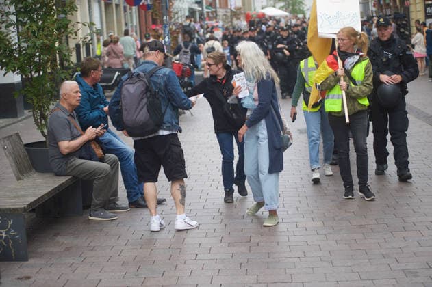 Flensburg, Schleswig-Holstein Demo ProjektM1llion öEinigkeit für Deutschland™. Hier: Zwei Personen verteilen Flyer an Passanten in der Flensburger Innenstadt. Im Hintergrund massiv Polizeiaufgebot. Aufnahme vom 18.07.2026, Flensburg. *** Flensburg, Schleswig-Holstein: Unity for Germany™ demonstration. Here, two people are handing out flyers to passersby in downtown Flensburg. In the background, a massive police presence. Photo taken on July 18, 2026, in Flensburg.