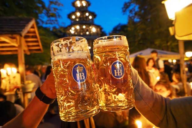 Kocherlball am Chinesischen Turm, Biertrinken bei Kerzenschein um 4:40 Uhr, München, 19. Juli 2026 Deutschland, München, 19. Juli 2026, Biertrinken bei Kerzenschein, traditioneller Kocherlball am Chinesischen Turm, Englischer Garten, zwei Besucher stoßen mit ihren Maßkrügen an, 4:40 Uhr in der früh, manche Besucher sind schon um 3 Uhr früh im Biergarten, um noch einen Platz zu ergattern, die Menschen trinken ein Bier, essen eine Brotzeit, tragen Tracht, Tradition entstand im 19. Jahrhundert, als Hauspersonal, Dienstboten und KöchInnen in den frühen Morgenstunden vor Dienstbeginn gefeiert und getanzt haben, Tradition wurde ab 1989 wiederbelebt, traditionell am 3. Sonntag im Juli, feiern, Tradition, traditionell, Bayern, typisch bay
