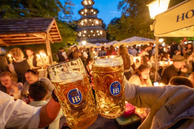 Kocherlball am Chinesischen Turm, Biertrinken bei Kerzenschein um 4:45 Uhr, München, 19. Juli 2026 Deutschland, München, 19. Juli 2026, Biertrinken bei Kerzenschein, traditioneller Kocherlball am Chinesischen Turm, Englischer Garten, zwei Besucher stoßen mit ihren Maßkrügen an, 4:45 Uhr in der früh, manche Besucher sind schon um 3 Uhr früh im Biergarten, um noch einen Platz zu ergattern, die Menschen trinken ein Bier, essen eine Brotzeit, tragen Tracht, Tradition entstand im 19. Jahrhundert, als Hauspersonal, Dienstboten und KöchInnen in den frühen Morgenstunden vor Dienstbeginn gefeiert und getanzt haben, Tradition wurde ab 1989 wiederbelebt, traditionell am 3. Sonntag im Juli, feiern, Tradition, traditionell, Bayern, typisch bay