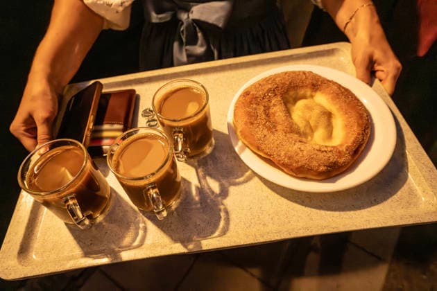 Kocherlball am Chinesischen Turm, Besucherin bevorzugt Kaffee statt Bier um 4:45 Uhr, München, 19. Juli 2026 Deutschland, München, 19. Juli 2026, Biertrinken bei Kerzenschein, Besucherin bevorzugt Kaffee und eine Ausgezogene, 4:45 Uhr, traditioneller Kocherlball am Chinesischen Turm, Englischer Garten, manche Besucher sind schon um 3 Uhr früh im Biergarten, um noch einen Platz zu ergattern, die Menschen trinken ein Bier, essen eine Brotzeit, tragen Tracht, Tradition entstand im 19. Jahrhundert, als Hauspersonal, Dienstboten und KöchInnen in den frühen Morgenstunden vor Dienstbeginn gefeiert und getanzt haben, Tradition wurde ab 1989 wiederbelebt, traditionell am 3. Sonntag im Juli, feiern, Tradition, traditionell, Bayern, typisch baye
