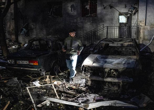 A man lights his way as he walks between two destroyed cars in the Solomianskyi district after a Russian attack on Kyiv, Ukraine, July 19, 2026. The Russian army launched a massive strike on the Ukrainian capital with ballistic missiles. According to preliminary data from the State Emergency Service of Ukraine, one person was killed and 15 were injured. Falling debris and fires were reported in five districts of the city, while an underpass near the Lukianivska metro station sustained a direct hit. (Photo by Danylo Antoniuk Ukrinform) Russian army attack Kyiv with ballistic missiles  Copyright: xDanyloxAntoniukx