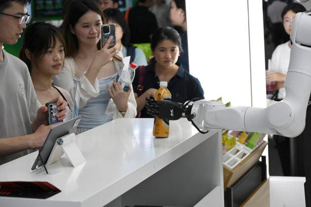 (260719) -- SHANGHAI, July 19, 2026 -- A robot hands beverage to visitors during the 2026 World AI Conference in Shanghai, east China, July 19, 2026. The ongoing 2026 World AI Conference turns out to be a highly competitive arena for general embodied AI products from more than 200 providers. It refers to a general-purpose intelligence system that enables robots to perform variable tasks and adapt to different application scenarios. ) CHINA-SHANGHAI-WORLD AI CONFERENCE-GENERAL EMBODIED AI (CN) HuangxXiaoyong 