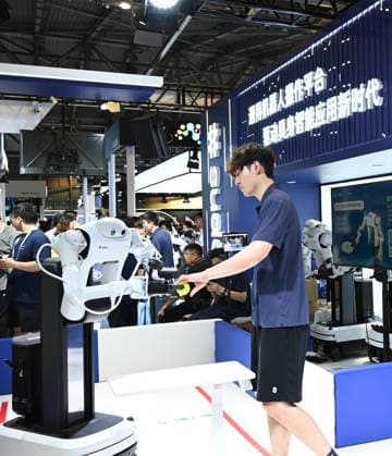 (260719) -- SHANGHAI, July 19, 2026 -- A robot takes over an object from a staff member during the 2026 World AI Conference in Shanghai, east China, July 19, 2026. The ongoing 2026 World AI Conference turns out to be a highly competitive arena for general embodied AI products from more than 200 providers. It refers to a general-purpose intelligence system that enables robots to perform variable tasks and adapt to different application scenarios. ) CHINA-SHANGHAI-WORLD AI CONFERENCE-GENERAL EMBODIED AI (CN) HuangxXiaoyong 