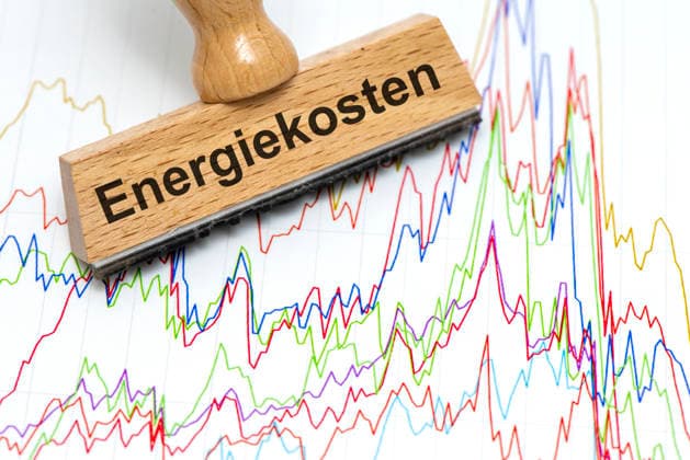 Energiekosten und Energiepreise Ein Holzstempel ist beschriftet mit dem Aufdruck Energiekosten als Symbolbild für steigende Kosten für Energie in Wirtschaft, Industrie und Handel - FOTOMONTAGE - NUR FÜR REDAKTIONELLE VERWENDUNG - *** Energy Costs and Energy Prices: A wooden stamp bears the inscription Energy Costs as a symbolic image representing rising energy costs in business, industry, and commerce. PHOTOMONTAGE FOR EDITORIAL USE ONLY