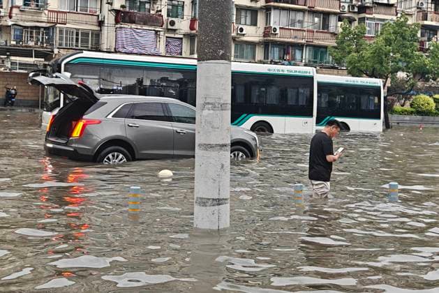 SHANGHAI, CHINA - JULY 19: A pedestrian wades through flooded street due to heavy rainstorms on July 19, 2026 in Shanghai, China. Heavy rain caused severe waterlogging in roads and residential areas in Shanghai s Yangpu District. Shanghai Meteorological Observatory upgraded the rainstorm alert from yellow to orange for the central urban area at 14:35 on July 19.  Copyright: xVCGx 111655264428