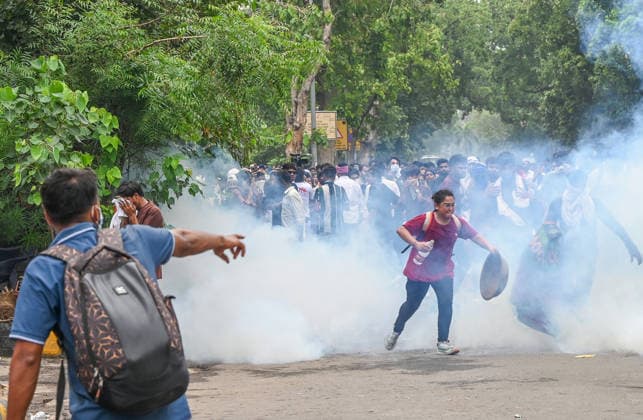 NEW DELHI, INDIA - JULY 20: CJP protestors use iron pan and wet cloth to stop tear gas hurled by Delhi Police to disperse supporters of the Cockroach Janta Party (CJP) after they gather in large numbers and breach security barricades on DR Rajendra Prasad Road near Parliament House on July 20, 2026 in New Delhi, India. The protesters were demanding the resignation of Union Education Minister Dharmendra Pradhan over alleged examination irregularities. (Photo by Ajay Aggarwal Hindustan Times) Delhi Police Use Lathi Charge And Tear Gas Shells To Disperse CJP Supporters During Their March To Parliament