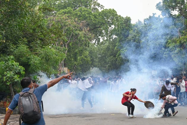 NEW DELHI, INDIA - JULY 20: CJP protestors use iron pan and wet cloth to stop tear gas hurled by Delhi Police to disperse supporters of the Cockroach Janta Party (CJP) after they gather in large numbers and breach security barricades on DR Rajendra Prasad Road near Parliament House on July 20, 2026 in New Delhi, India. The protesters were demanding the resignation of Union Education Minister Dharmendra Pradhan over alleged examination irregularities. (Photo by Ajay Aggarwal Hindustan Times) Delhi Police Use Lathi Charge And Tear Gas Shells To Disperse CJP Supporters During Their March To Parliament