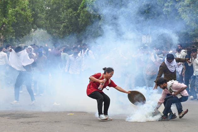 NEW DELHI, INDIA - JULY 20: A CJP protestor use iron pan and wet cloth to stop tear gas hurled by Delhi Police to disperse supporters of the Cockroach Janta Party (CJP) after they gather in large numbers and breach security barricades on DR Rajendra Prasad Road near Parliament House on July 20, 2026 in New Delhi, India. The protesters were demanding the resignation of Union Education Minister Dharmendra Pradhan over alleged examination irregularities. (Photo by Ajay Aggarwal Hindustan Times) Delhi Police Use Lathi Charge And Tear Gas Shells To Disperse CJP Supporters During Their March To Parliament