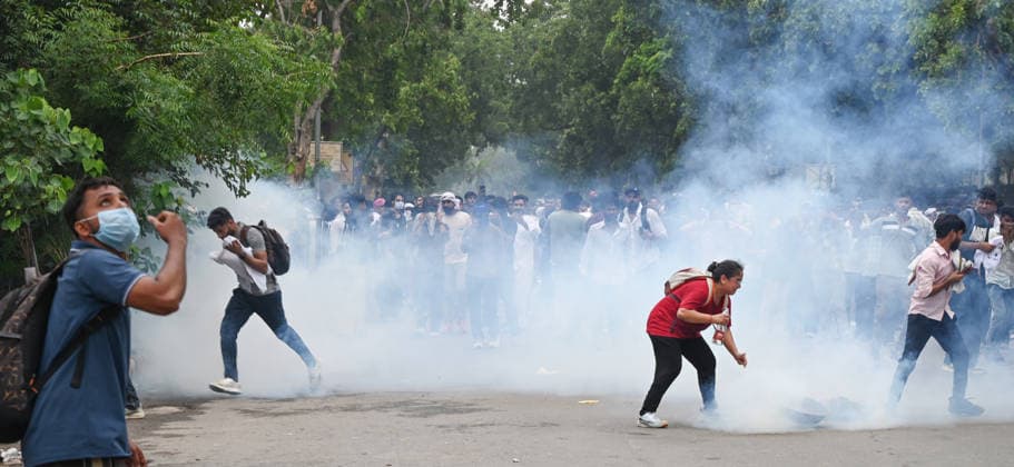 NEW DELHI, INDIA - JULY 20: A CJP protestor use iron pan and wet cloth to stop tear gas hurled by Delhi Police to disperse supporters of the Cockroach Janta Party (CJP) after they gather in large numbers and breach security barricades on DR Rajendra Prasad Road near Parliament House on July 20, 2026 in New Delhi, India. The protesters were demanding the resignation of Union Education Minister Dharmendra Pradhan over alleged examination irregularities. (Photo by Ajay Aggarwal Hindustan Times) Delhi Police Use Lathi Charge And Tear Gas Shells To Disperse CJP Supporters During Their March To Parliament
