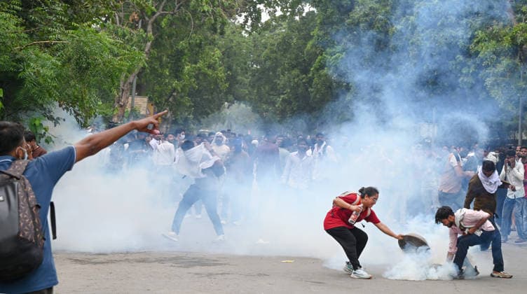 NEW DELHI, INDIA - JULY 20: A CJP protestor use iron pan and wet cloth to stop tear gas hurled by Delhi Police to disperse supporters of the Cockroach Janta Party (CJP) after they gather in large numbers and breach security barricades on DR Rajendra Prasad Road near Parliament House on July 20, 2026 in New Delhi, India. The protesters were demanding the resignation of Union Education Minister Dharmendra Pradhan over alleged examination irregularities. (Photo by Ajay Aggarwal Hindustan Times) Delhi Police Use Lathi Charge And Tear Gas Shells To Disperse CJP Supporters During Their March To Parliament