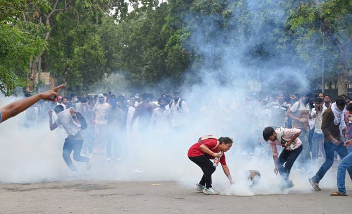 NEW DELHI, INDIA - JULY 20: A CJP protestor use iron pan and wet cloth to stop tear gas hurled by Delhi Police to disperse supporters of the Cockroach Janta Party (CJP) after they gather in large numbers and breach security barricades on DR Rajendra Prasad Road near Parliament House on July 20, 2026 in New Delhi, India. The protesters were demanding the resignation of Union Education Minister Dharmendra Pradhan over alleged examination irregularities. (Photo by Ajay Aggarwal Hindustan Times) Delhi Police Use Lathi Charge And Tear Gas Shells To Disperse CJP Supporters During Their March To Parliament