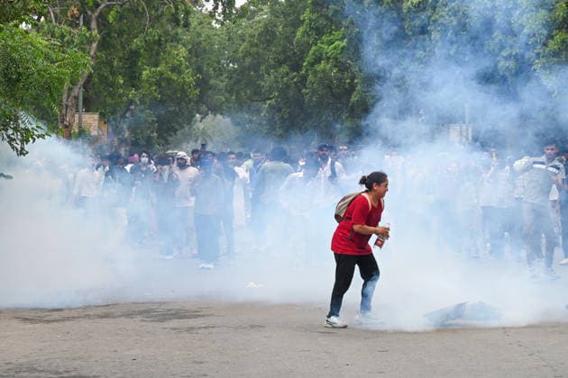 NEW DELHI, INDIA - JULY 20: A CJP protestor use iron pan and wet cloth to stop tear gas hurled by Delhi Police to disperse supporters of the Cockroach Janta Party (CJP) after they gather in large numbers and breach security barricades on DR Rajendra Prasad Road near Parliament House on July 20, 2026 in New Delhi, India. The protesters were demanding the resignation of Union Education Minister Dharmendra Pradhan over alleged examination irregularities. (Photo by Ajay Aggarwal Hindustan Times) Delhi Police Use Lathi Charge And Tear Gas Shells To Disperse CJP Supporters During Their March To Parliament