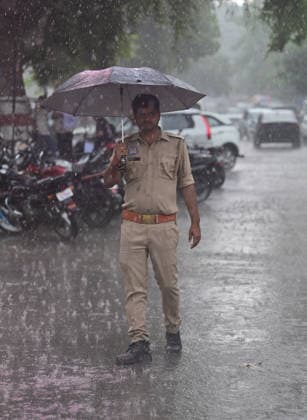 July 20, 2026, Prayagraj, Uttar Pradesh, India: Prayagraj: A policeman walks with an umbrella during Rain, in Prayagraj on Monday, July 20, 2026. Prayagraj India - ZUMAv115 20260720_zap_v115_052 Copyright: xPrabhatxKumarxVermax
