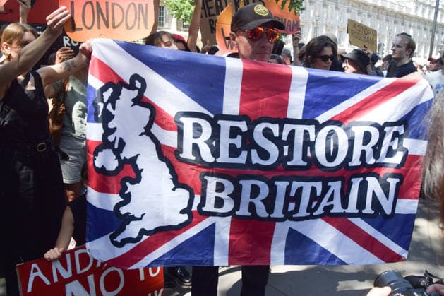July 20, 2026, London, England, United Kingdom: A right-wing protester holding a Union Jack emblazoned with Restore Britain confronts climate activists from the group Fossil Free London staging a protest outside Downing Street against Rosebank and other oil and gas projects in the North Sea ahead of the arrival of Andy Burnham, who replaces Keir Starmer as the UK Prime Minister. London United Kingdom  - ZUMAv130 20260720_zip_v130_038 Copyright: xVukxValcicx
