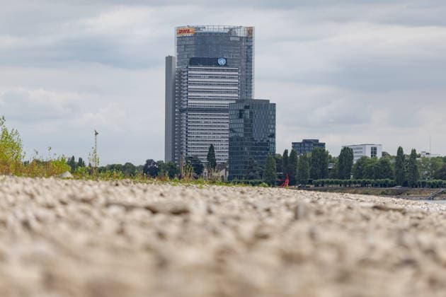 Niedrigwasser am Rhein vor dem UN Campus in Bonn Niedrigwasser am Rhein: Bei einem Pegelstand von 125 cm am Pegel Bonn liegt das Flussbett bis auf die tiefer liegende Fahrrinne trocken. Im Hintergrund das Hochhaus-Ensemble aus Post Tower, Langer Eugen und Climate Tower auf dem UN Campus, wo das Sekretariat der UN-Klimarahmenkonvention UNFCCC über den globalen Klimaschutz verhandelt. Bonn Beuel Nordrhein-Westfalen Deutschland *** Low Water Levels on the Rhine in Front of the UN Campus in Bonn Low Water Levels on the Rhine With the water level at 125 cm at the Bonn gauge, the riverbed is dry except for the lower-lying navigation channel. In the background is the high-rise complex consisting of the Post Tower, Langer Eugen, and Climate Tower Copyright: xMarcxJohnx