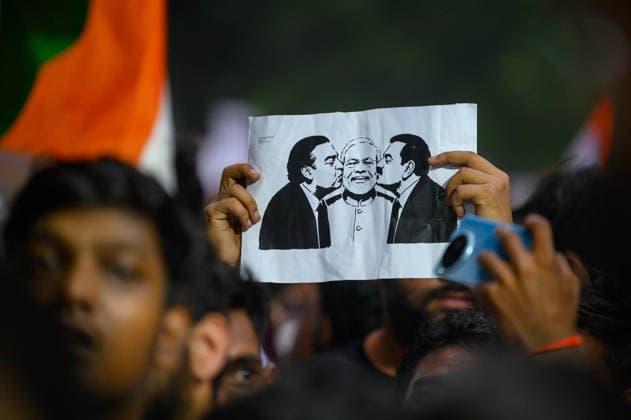 July 20, 2026, New Delhi, New Delhi, India: A protester holds up a placard depicting billionaires Mukesh Ambani and Gautam Adani kissing the cheeks of Prime Minister Narendra Modi, symbolizing protesters allegations of a corruption nexus between the two industrialists and the Modi government, at Jantar Mantar during demonstrations by the Cockroach Janata Party (CJP) demanding the resignation of Education Minister Dharmendra Pradhan over alleged irregularities in the NEET-UG exam, July 20, 2026. New Delhi India  - ZUMAm184 20260720_zip_m184_010 Copyright: xAnkitxRoyxMajumderx