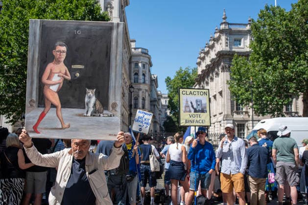 July 20, 2026, London, England, United Kingdom: A lots of people gathered outside Downing Street to support and protest against the new Prime Minister of the United Kingdom, Andy Burnham..Kaya Mar is a London-based satirical painter and caricaturist holds his painting about the New British Prime Minister, Andy Burnham outside Downing Street in London. London United Kingdom  - ZUMAe120 20260720_zip_e120_003 Copyright: xKrisztianxElekx