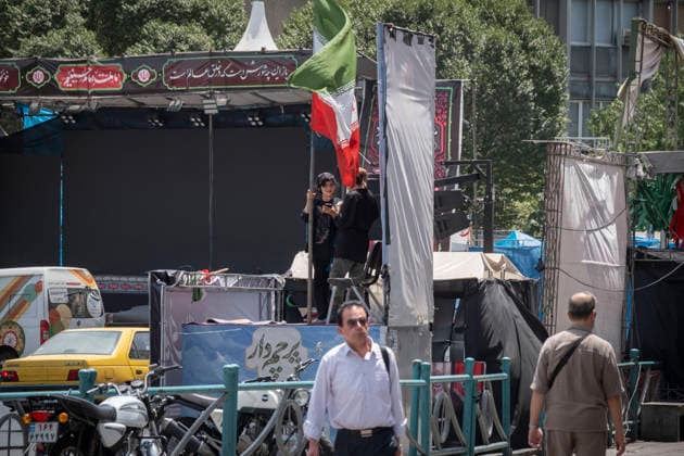 Anti‘Trump Messaging Appears On Billboards In Tehran A young female pro-government supporter holding an Iranian national flag uses her smart phone as she stands on a stage in downtown Tehran, Iran, on July 21, 2026, amid renewed conflicts between Iran and the United States in southern Iran. MORTEZA NIKOUBAZL NurPhoto Tehran Tehran Iran  Copyright: xMortezaxNikoubazlx originalFilename: nikoubazl-antitrum260721_np2Zy.jpg