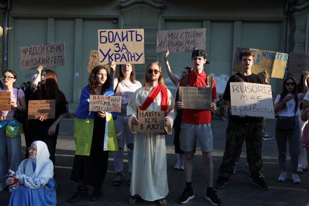 Rally in support of Mykhailo Fedorov in Odessa, Ukraine - 21 Jul 2026 A protester ontop of anothers shoulders holds a placard reading Even Jesus is in shock during a demonstration on Deribasovskaya Street. Mass rally in support of former Ukrainian Defense Minister Mykhailo Fedorov, who was dismissed in mid-July, continue for the sixth day in major Ukrainian cities. Activists are demanding that the president reinstate Fedorov and dismiss Oleksandr Syrskyi, Commander-in-Chief of the Ground Forces of the Armed Forces of Ukraine. Odessa Ukraine Copyright: xViacheslavxOnyshchenkox xSOPAxImagesx Vonyshchenko(2)