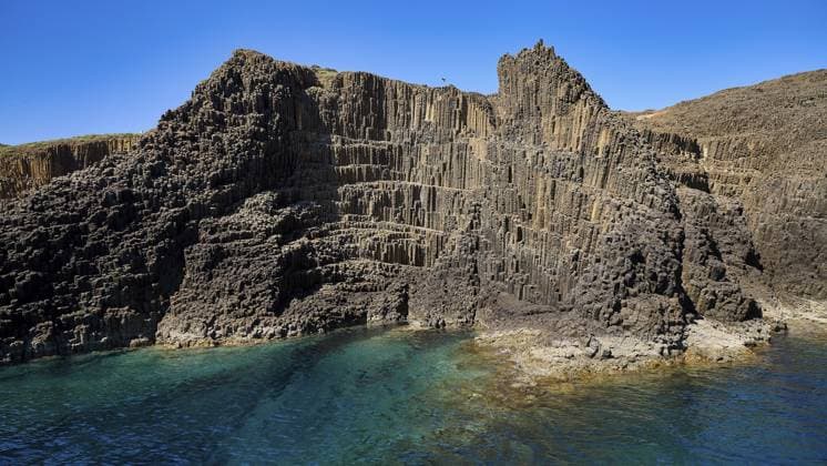 Creative Highlights World Eine beeindruckende Klippenlandschaft mit markanten Basaltsäulen und blauem Meer, Glaronisia, Glaronesia, Milos, Inselchen, Hexagonale Basaltsäulen, nördlich von Milos, Ausflugsziel per Boot, Kykladen, Griechische Inseln, Griechenland An impressive cliff landscape with distinctive basalt columns and blue sea, Glaronisia, Glaronesia, Milos, islets, hexagonal basalt columns, north of Milos, destination by boat, Cyclades, Greek Islands, Greece Copyright: imageBROKER RalfxAdler ibxraa18367795.jpg