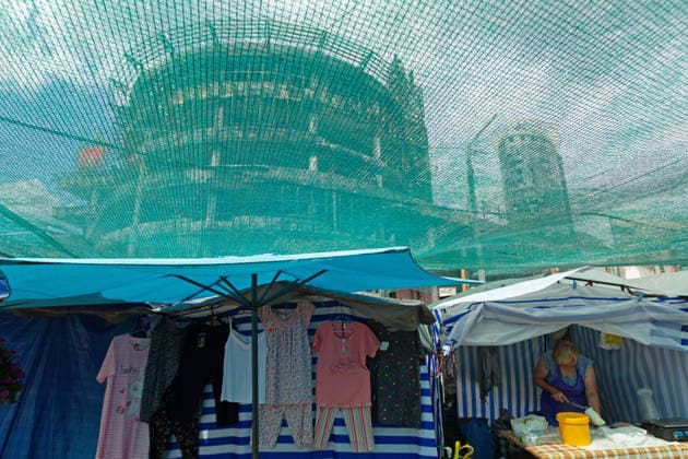 A woman sells dairy products next to a stall with clothes at the market near the Lukianivska metro station, which reopened after the recent massive Russian bombardment, beside the Kvadrat shopping centre destroyed in the large-scale Russian attack on the night of May 23–24, 2026, Kyiv, Ukraine, July 21, 2026. On Sunday night, July 19, 2026, Russia launched a massive missile strike on the Ukrainian capital. The Lukianivka historical neighbourhood was hit again. The strike damaged the Lukianivska metro station, its vestibule and foyer, and wrecked the Lukianivka market. The underground passage on Yuriia Illienka Street was also directly struck. (Photo by Kyrylo Chubotin Ukrinform) Lukianivka neighbourhood in Kyiv recovers from massive Russian  Copyright: xKyryloxChubotinx