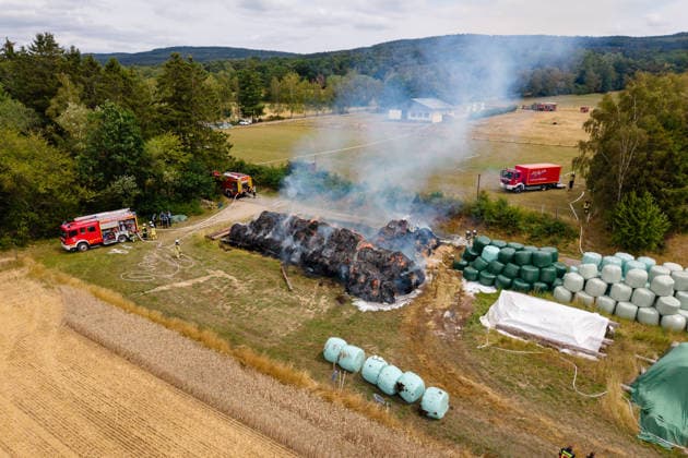 Polizeihubschrauber sucht nach Brandstiftern 200 Rundballen in Flammen 70 Einsatzkräfte im Einsatz Am 22.07.2026 brannten in Tiefenbach im Hunsrück gegen 13:00 Uhr rund 200 Rundballen an drei nahegelegenen Einsatzstellen. Zwei Brandstellen lagen im Wald, eine auf einem Sportplatz. Ein Polizeihubschrauber suchte das Gebiet nach möglichen Tätern ab, während die Polizei Fahrzeuge auf der Straße kontrollierte. Rund 70 Einsatzkräfte errichteten eine Riegelstellung zu angrenzenden Silageballen und dem Wald und ließen das Feuer kontrolliert abbrennen. Tiefenbach (Hunsrück) Rheinland-Pfalz Deutschland *** Police helicopter searches for arsonists; 200 round bales in flames; 70 emergency responders on the scene. On July 22, 2026, at
