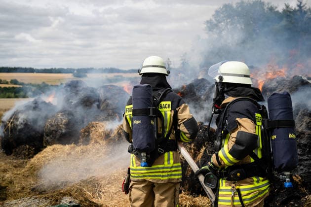 Polizeihubschrauber sucht nach Brandstiftern 200 Rundballen in Flammen 70 Einsatzkräfte im Einsatz Am 22.07.2026 brannten in Tiefenbach im Hunsrück gegen 13:00 Uhr rund 200 Rundballen an drei nahegelegenen Einsatzstellen. Zwei Brandstellen lagen im Wald, eine auf einem Sportplatz. Ein Polizeihubschrauber suchte das Gebiet nach möglichen Tätern ab, während die Polizei Fahrzeuge auf der Straße kontrollierte. Rund 70 Einsatzkräfte errichteten eine Riegelstellung zu angrenzenden Silageballen und dem Wald und ließen das Feuer kontrolliert abbrennen. Tiefenbach (Hunsrück) Rheinland-Pfalz Deutschland *** Police helicopter searches for arsonists; 200 round bales in flames; 70 emergency responders on the scene. On July 22, 2026, at