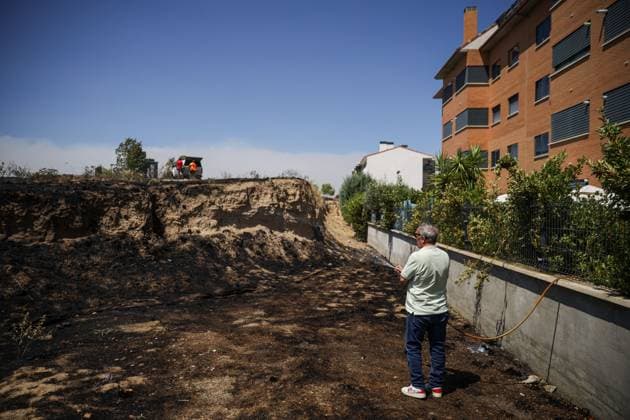 July 24, 2026, Navalcarnero, Spain: NAVALCARNERO, SPAIN Ã¢â‚¬ JULY 24, 2026: Municipal workers and local residents carry out cooling operations while tractors create firebreaks after a vegetation fire broke out near residential areas in Navalcarnero, Madrid. Emergency services worked to secure the affected area and prevent the flames from spreading further amid high temperatures and dry conditions. Navalcarnero Spain - ZUMAq101 20260724_zna_q101_092 Copyright: xEugenioxRodriguezxRigox
