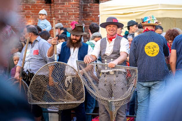 Ein Blick auf das traditionelle Bachausfischen während des Fischertags in Memmingen. Zahlreiche Fischer in teils historischer Kleidung waten durch den Stadtbach, um Fische zu fangen. Dicht gedrängt stehen Zuschauer am Ufer und verfolgen das Spektakel, das jährlich tausende Besucher anzieht. Im Hintergrund sind die historischen Mauern der Stadt zu sehen. Der Memminger Fischertag ist eines der ältesten und bekanntesten Volksfeste in Bayern. Memmingen Bayern Deutschland *** A look at the traditional stream fishing during Fishermen’s Day in Memmingen. Numerous fishermen, some in historical attire, wade through the town stream to catch fish. Spectators stand crowded together on the bank, watching the spectacle, which attracts thousands of