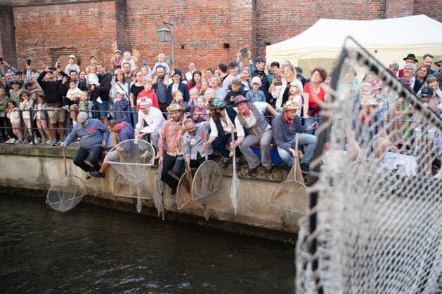 Ein Blick auf das traditionelle Bachausfischen während des Fischertags in Memmingen. Zahlreiche Fischer in teils historischer Kleidung waten durch den Stadtbach, um Fische zu fangen. Dicht gedrängt stehen Zuschauer am Ufer und verfolgen das Spektakel, das jährlich tausende Besucher anzieht. Im Hintergrund sind die historischen Mauern der Stadt zu sehen. Der Memminger Fischertag ist eines der ältesten und bekanntesten Volksfeste in Bayern. Memmingen Bayern Deutschland *** A look at the traditional stream fishing during Fishermen’s Day in Memmingen. Numerous fishermen, some in historical attire, wade through the town stream to catch fish. Spectators stand crowded together on the bank, watching the spectacle, which attracts thousands of