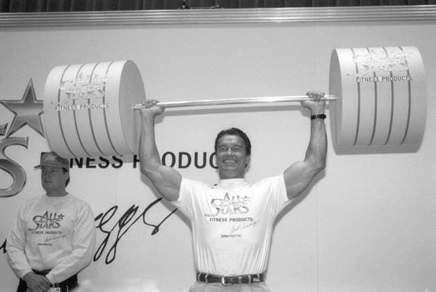 Arnold Schwarzenegger (Schauspieler) 04 93 mat Arnold Schwarzenegger auf der FIBO in Essen im April 1993 Weltmesse für Fitness und Freizeit Messe Sportmesse Fitnessmesse Österreich österreichisch österreichischer Österreicher USA US-amerikanisch amerikanischer US-Amerikaner Mann Schauspieler Bodybuilder Mr. Universum Kino Spielfilm austrian american actor quer halb stehend Gewichte stemmend Langhantel Hantel lächelnd sw *** Arnold Schwarzenegger, actor, April 1993: Arnold Schwarzenegger at FIBO in Essen in April 1993—World Trade Fair for Fitness and Leisure, Sports Fair, Fitness Fair, Austria, Austrian, Austrian man, USA, US, American, American man, actor, bodybuilder, Mr. Universe, cinema, feature film, Austrian, American